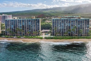 Ein Hotel direkt am Strand mit mehreren Hochhäusern, einem Strand und einer bergigen Kulisse.
