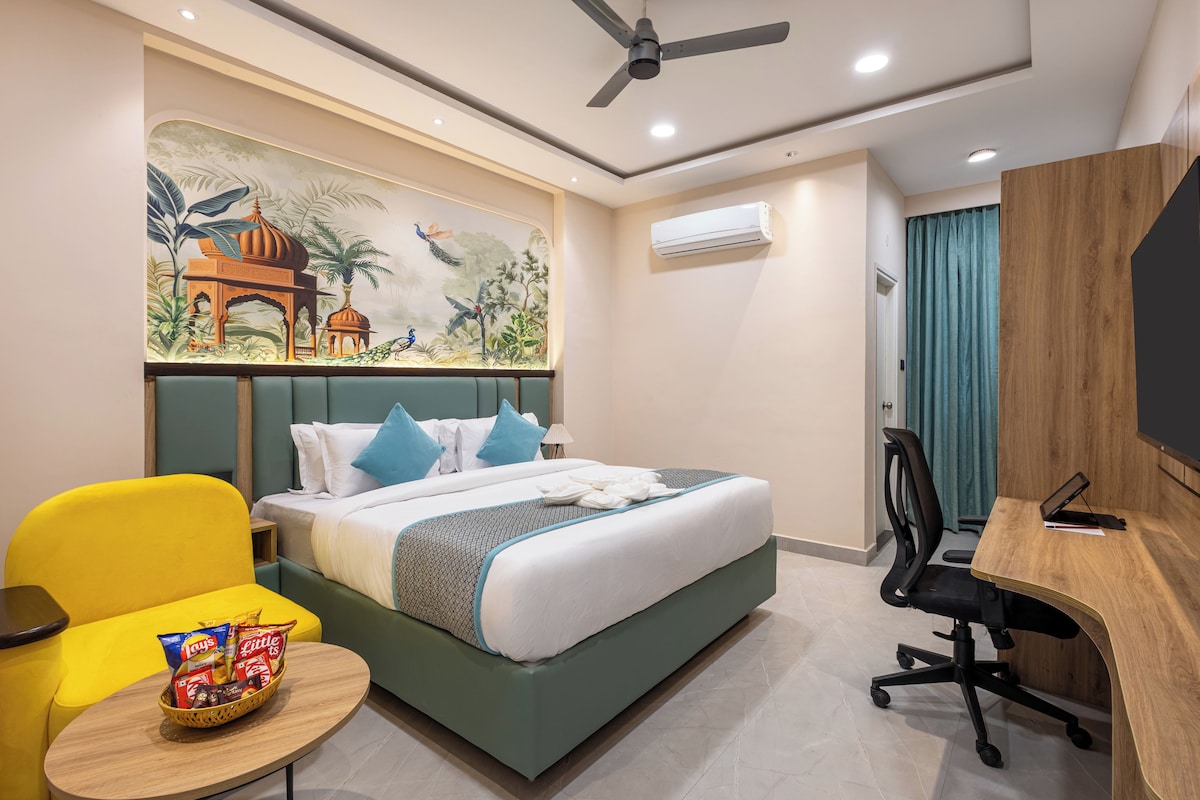 Una habitación de hotel con cama, escritorio, silla, aire acondicionado de pared y ventilador de techo.
