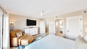 Une chambre à coucher comprenant un lit, un canapé, une télévision, une commode et une armoire.