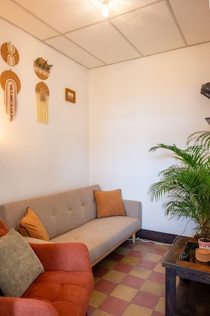 A living room with a sofa, a smaller couch, a coffee table, and a potted plant. - 360° Volcano View Apartment - Central Antigua (Antigua Guatemala)