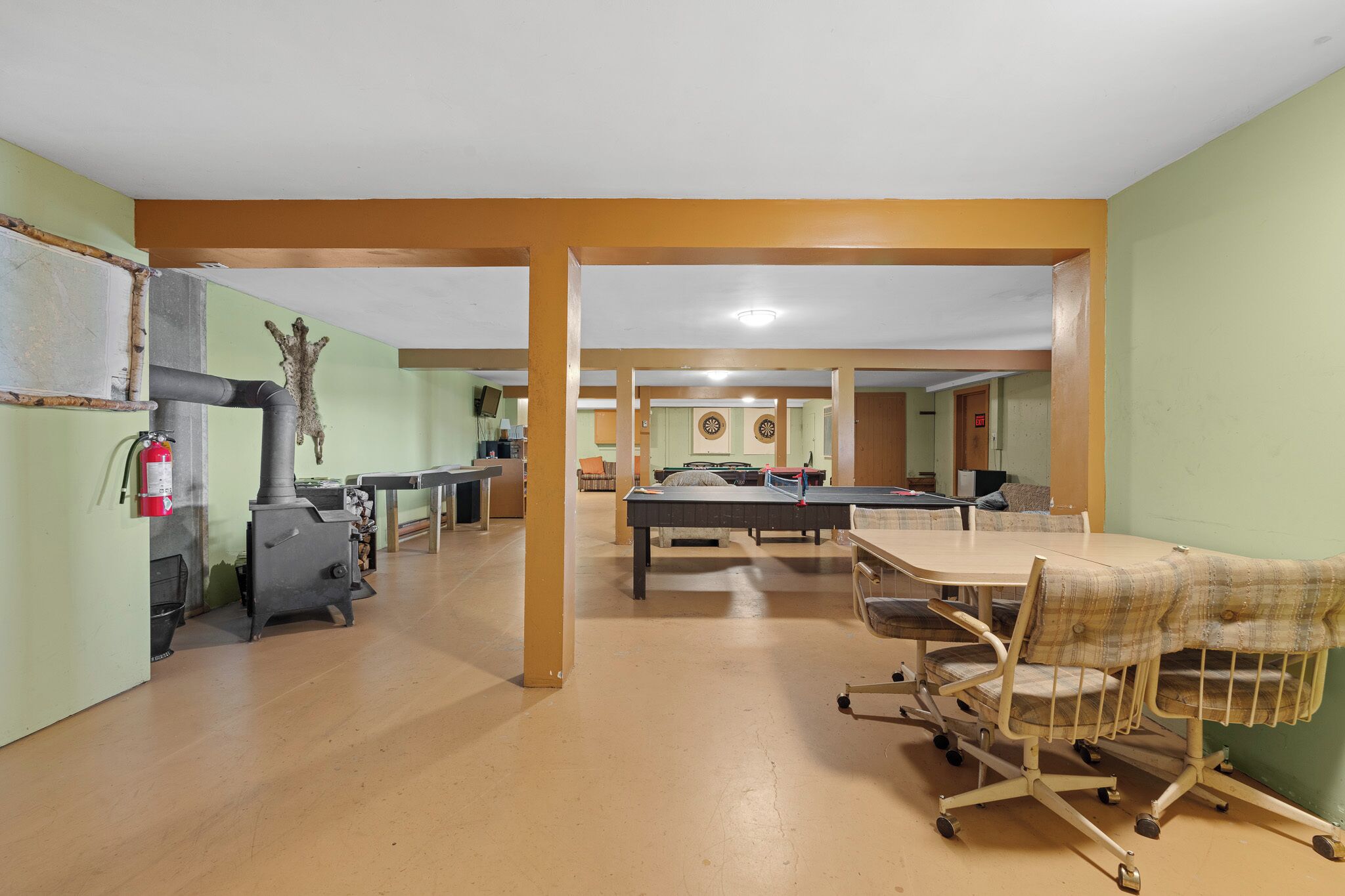 A spacious room with a ping pong table, a fireplace, and a dartboard.