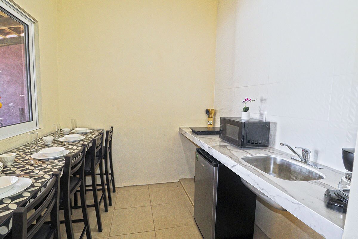 Une cuisine compacte comprenant une table à manger pour quatre personnes, un four à micro-ondes, un évier et un lave-vaisselle.