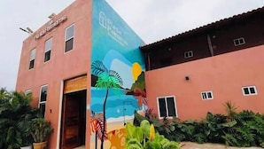 A building with a mural of a beach scene, a red facade, and a door.
