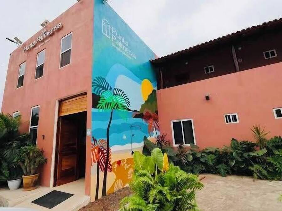 A building with a mural of a beach scene, a red facade, and a door.