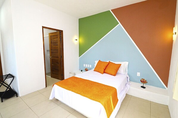 A hotel room with a bed, a nightstand, a wall clock, and a door.