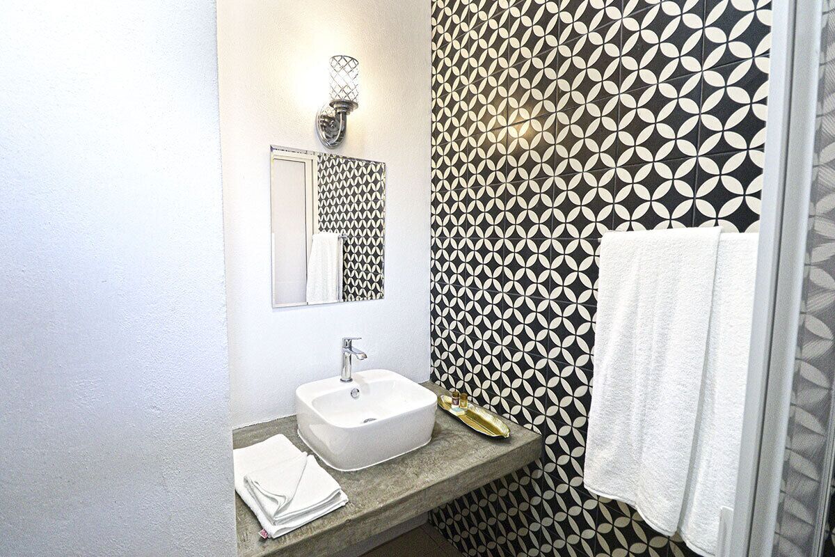 Un baño con un lavamanos blanco, un espejo y una pared con diseño.