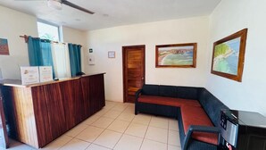 A reception area with a wooden desk, a sofa, and two framed pictures on the wall.