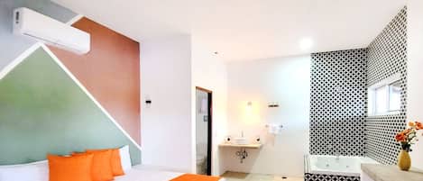 A hotel room with a bed, a bathroom with a bathtub, and a shower area.