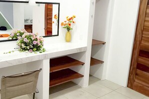 Un baño con tocador blanco, un espejo, un florero con flores y una silla.