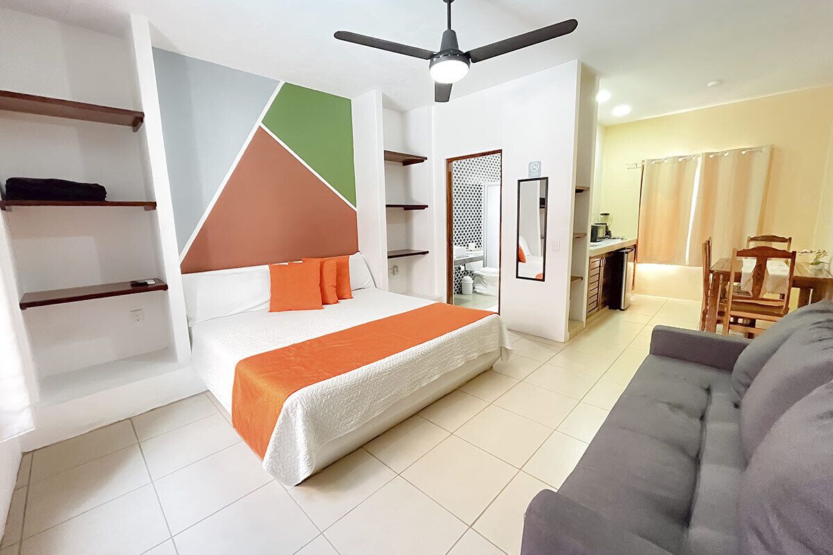 A modern bedroom with a bed, a ceiling fan, and a dining area with chairs and a table.