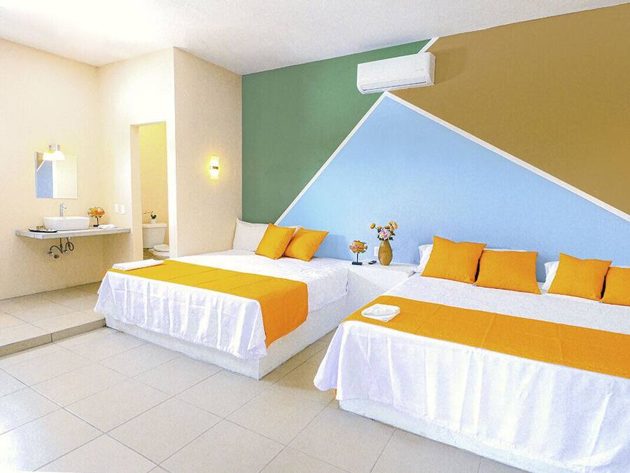 A hotel room with two beds, a bathroom, and a green wall.