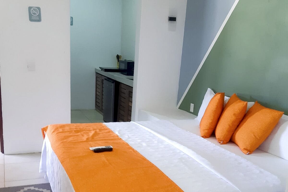Un dormitorio con una cama, un edredón naranja y tres almohadas naranjas.