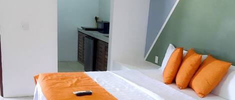Un dormitorio con una cama, un edredón naranja y tres almohadas naranjas.