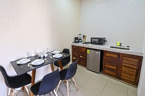 Une cuisine compacte équipée d’une table à manger pour deux personnes, d’un four à micro-ondes et d’un lave-vaisselle.