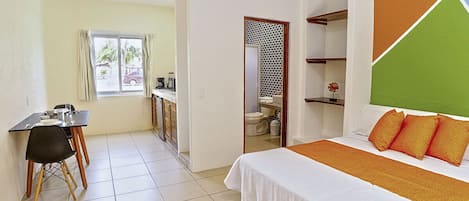 A hotel room with a bed, a desk, and a view of the outside.