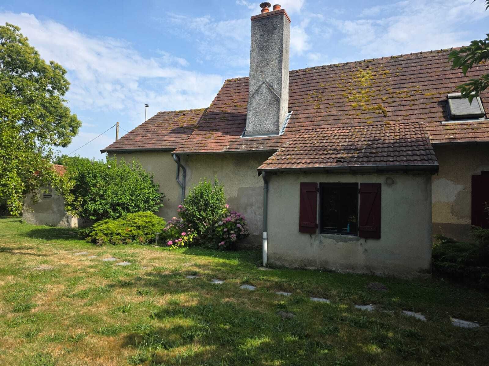 Ein Haus mit Schornstein, ein kleiner Anbau mit Fenster und ein Rasen.