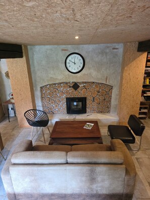 A cozy living area with a fireplace, a clock, and a sofa. - Charming home, relaxation area, pets, nature, tranquility, activities (CHEZY)
