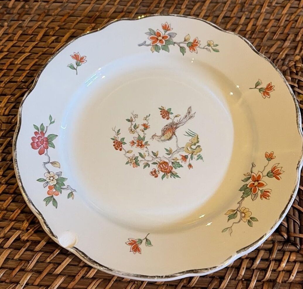 Un plato blanco con diseños florales y de pájaros sobre una superficie tejida.