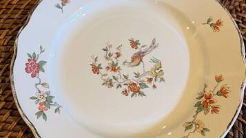 Un plato blanco con diseños florales y de pájaros sobre una superficie tejida.