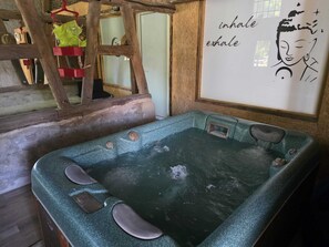 Ett spa-rum med ett bubbelbad, träbjälkar och en vägg med ett citat.