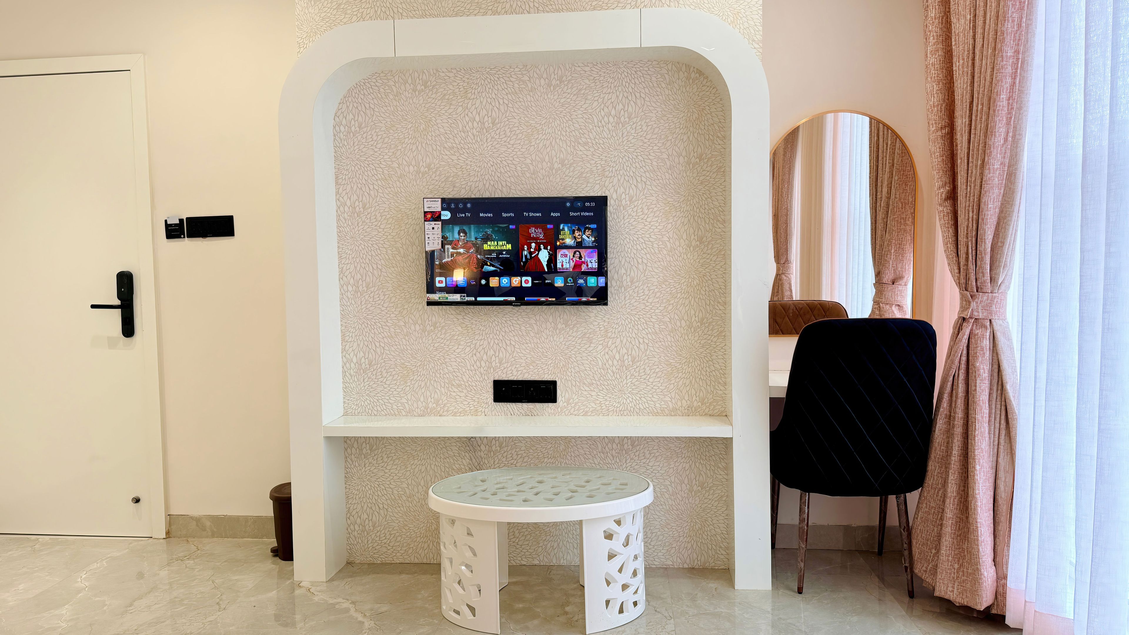 Una habitación moderna con televisión de pared, una mesita y una silla.