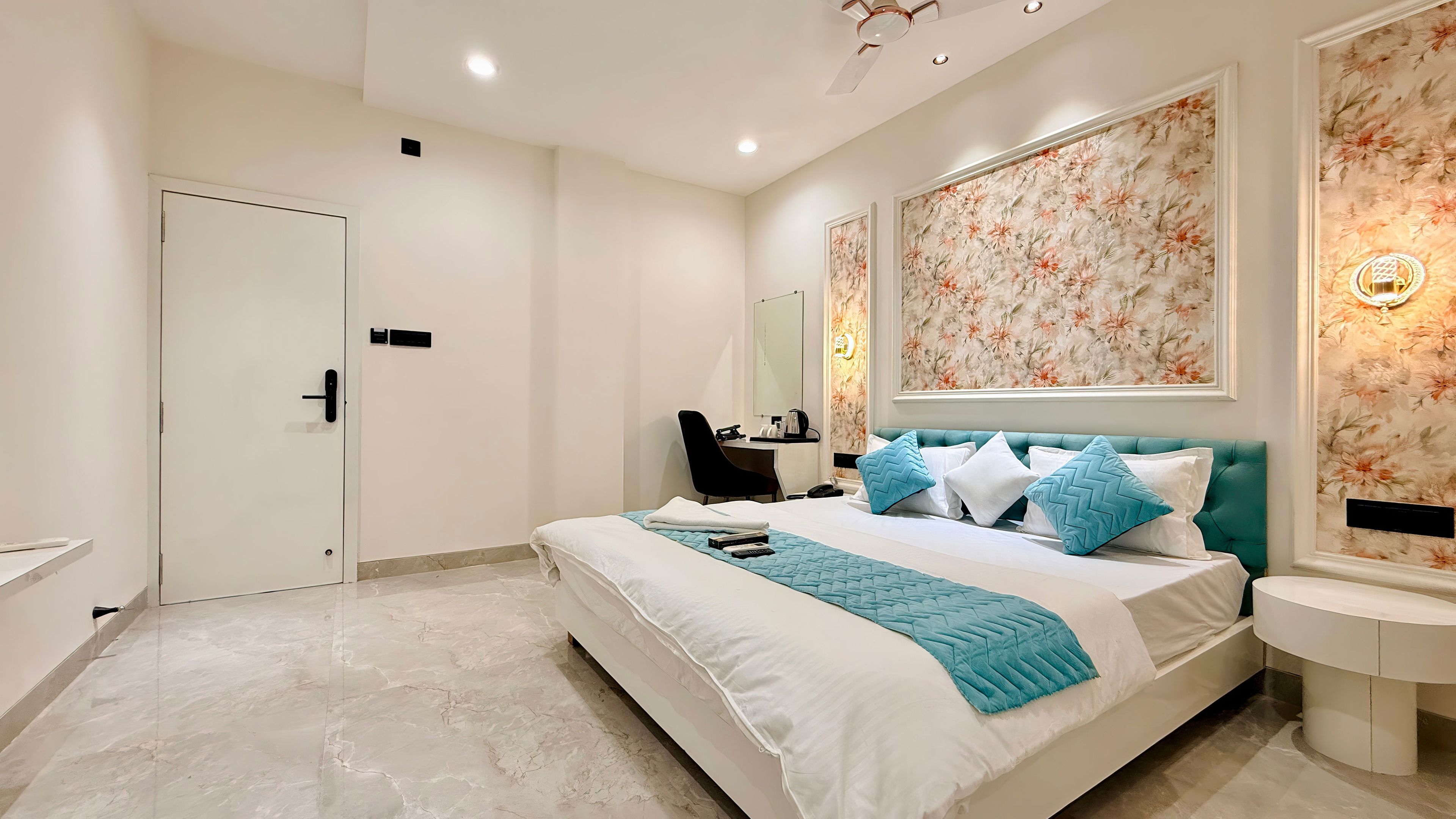 A hotel room with a bed, a desk, a chair, a bedside table, and a bathroom.