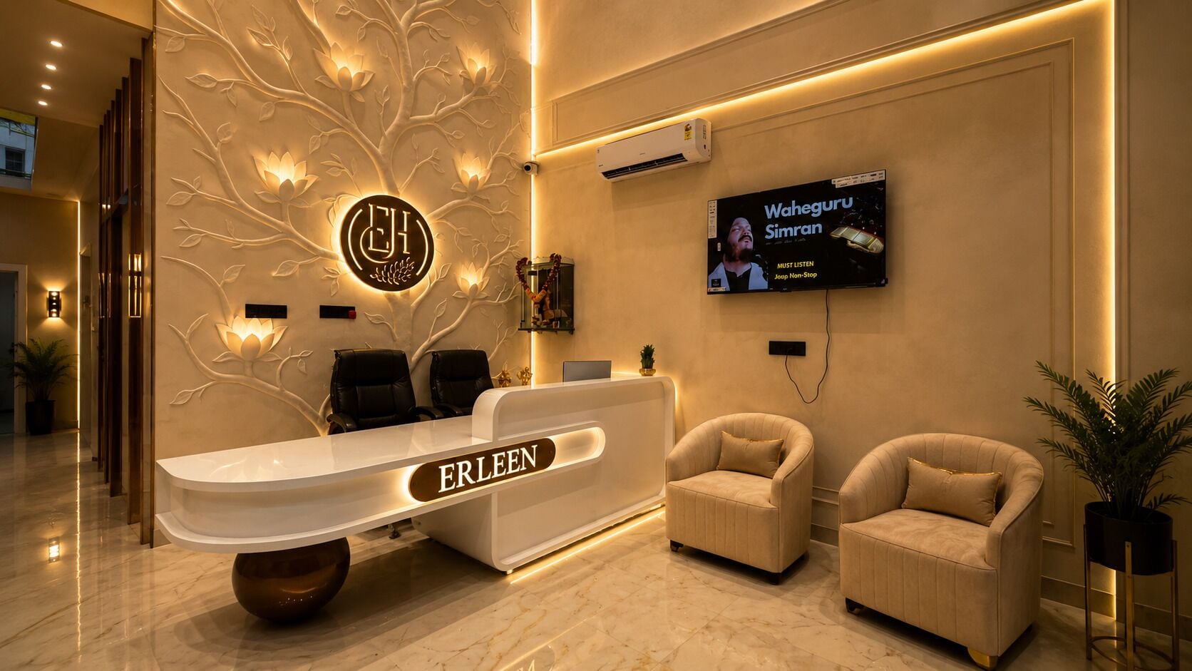 A reception desk with a nameplate, two chairs, a wall-mounted TV, and a decorative tree design.