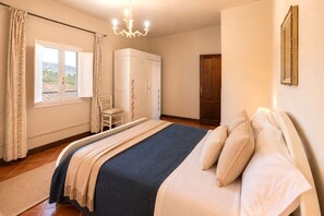 A bedroom with a bed, a chair, a wardrobe, and a window with curtains. - Gaetano Spadaro Estate, Frantoio Apartment on the Po River (Capannori)