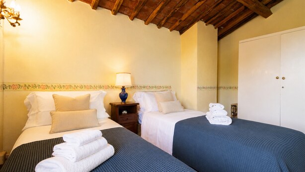 A hotel room with two beds, a nightstand with a lamp, and a wardrobe. - Gaetano Spadaro Estate, Frantoio Apartment on the Po River (Capannori)