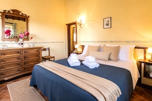 Ein Hotelzimmer mit einem großen Bett, einem Schminktisch, einem Spiegel und einer Blumenvase.