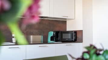 A modern kitchen with a built-in microwave, a coffee maker, and a scale on the countertop.