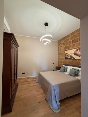 Ein Schlafzimmer mit einem Bett, einem Holzschrank, einer Steinsäule und einem Gemälde.