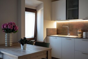 Eine moderne Küche mit weißen Schränken, einer Spüle aus Edelstahl und einem Holzespeisetisch mit Stühlen.