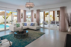 Ein modernes Wohnzimmer mit einem Ecksofa, einem Couchtisch und Blick auf einen Pool durch große Glasüren.