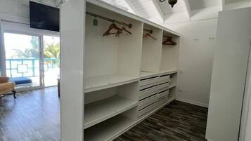 Una habitación con techo inclinado, suelo de madera y una estantería empotrada con perchas.