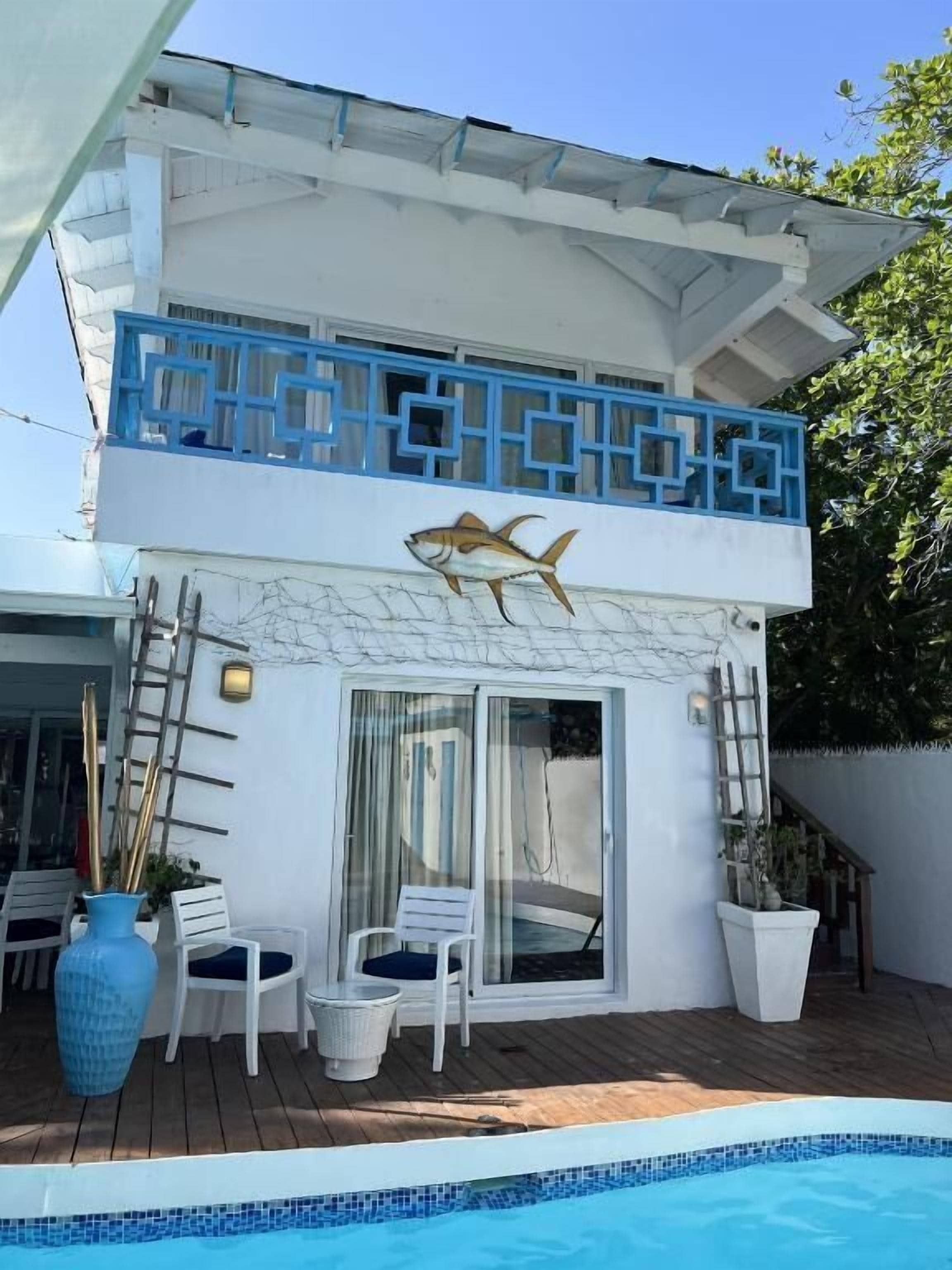 A two-story building with a swimming pool, outdoor seating, and a decorative fish mural.