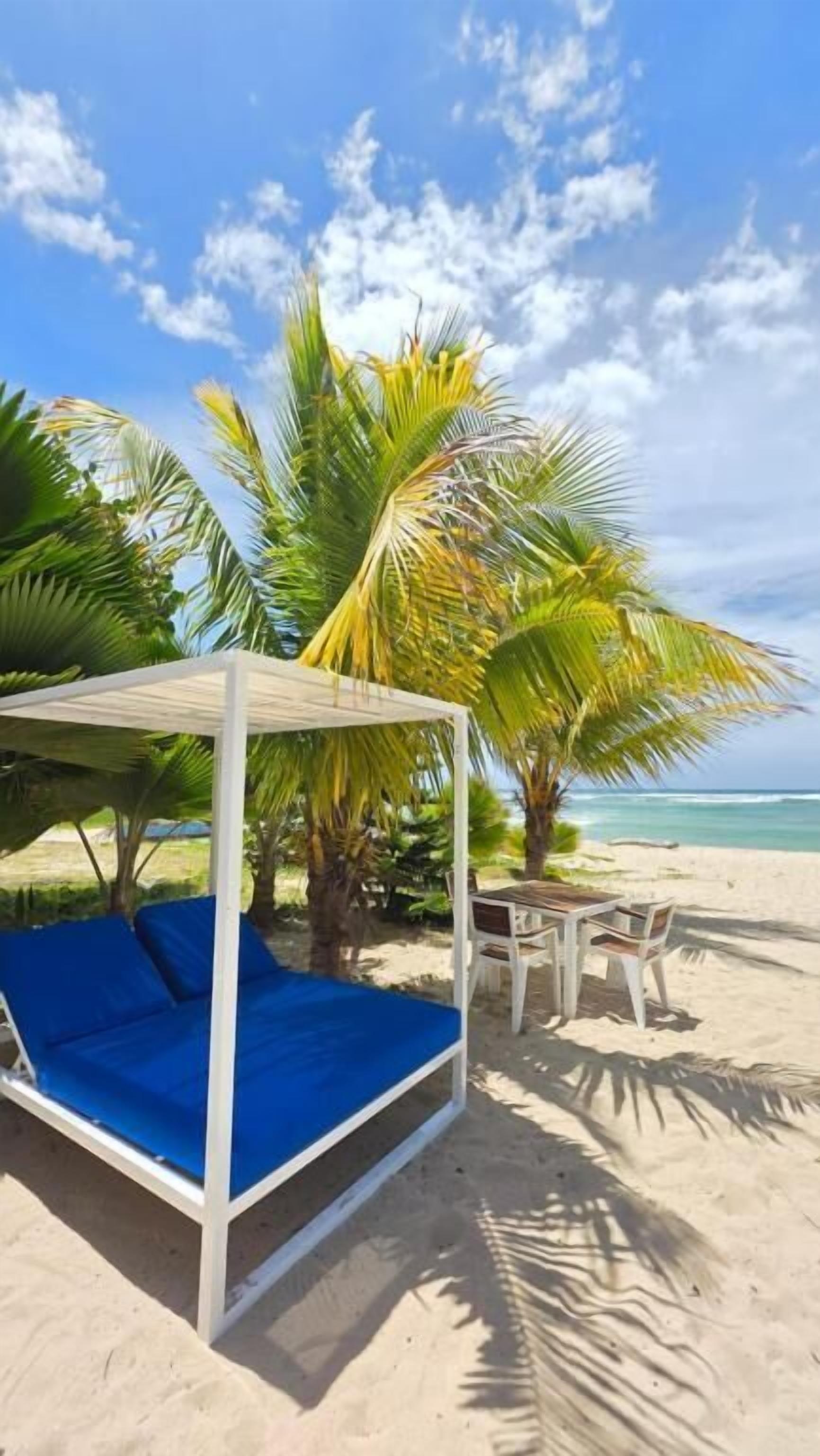 Un entorno de playa con una cama con dosel, una mesa y sillas.