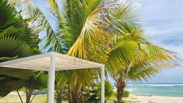 Un entorno de playa con una cama con dosel, una mesa y sillas.