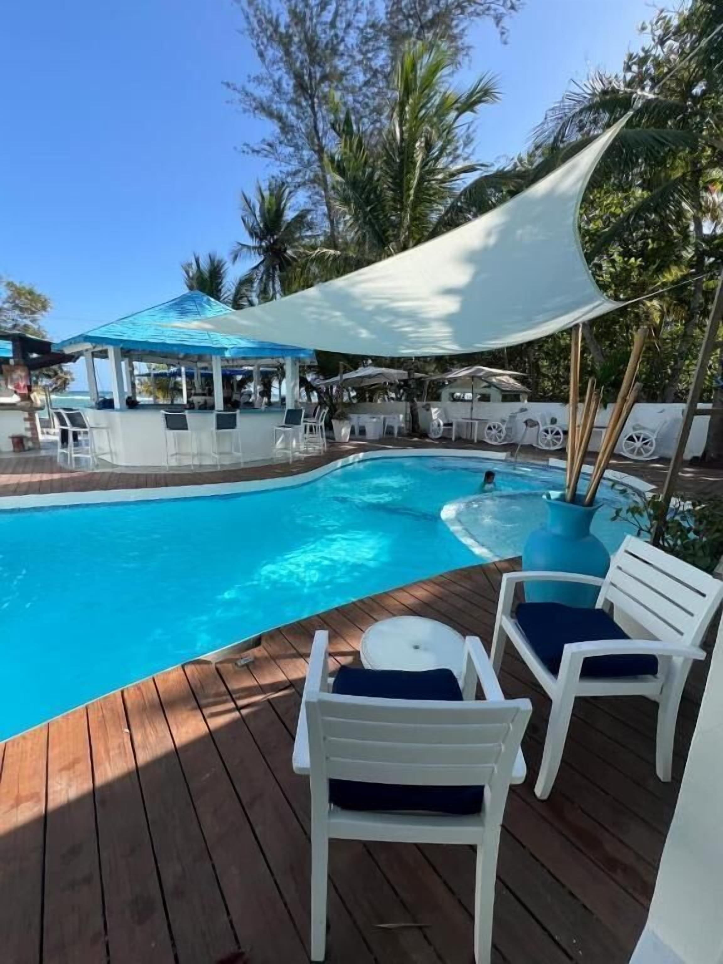 Zona de piscina con sillas de descanso y una sombrilla.