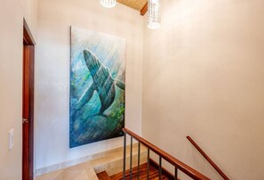 A staircase with a wooden handrail and a large abstract painting on the wall. - Beachfront Villa, Ocean Views, Resort Pools, Steps to Playa Flamingo (Playa Flamingo)