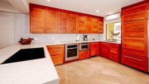A modern kitchen with wooden cabinets, stainless steel appliances, and a white countertop. - Beachfront Villa, Ocean Views, Resort Pools, Steps to Playa Flamingo (Playa Flamingo)