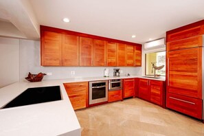 Eine moderne Küche mit Holzschränken, Edelstahlgeräten und einer weißen Arbeitsplatte.