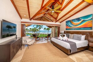 A hotel room with a bed, a view of the ocean, a painting, and a balcony with chairs. - Beachfront Villa, Ocean Views, Resort Pools, Steps to Playa Flamingo (Playa Flamingo)