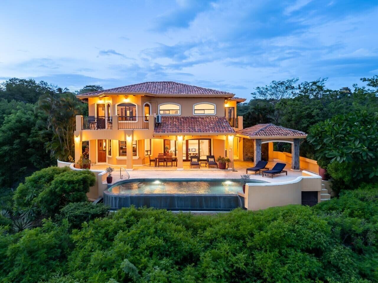A two-story house with a swimming pool, outdoor seating, and a covered patio.