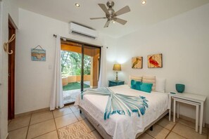 Ein Schlafzimmer mit Bett, Nachttisch, Lampe und Blick ins Freie.