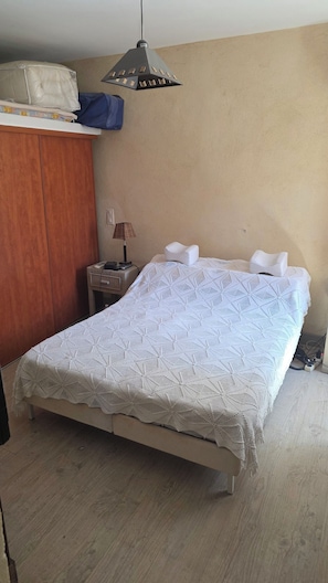 A bedroom with a bed, a wardrobe, a lamp, and a hanging light fixture. - Village house (Castifao)