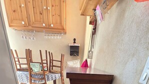 A wooden interior with a dining table and chairs, a kitchen counter, and a mat with 'Maison de Famille' text. - Village house (Castifao)
