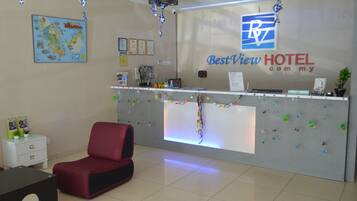 A reception desk with a logo, a map, certificates, and a red chair.