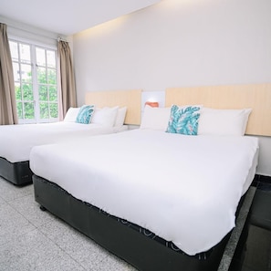 Habitación de hotel con dos camas, ventana con cortinas y vistas a zonas verdes.