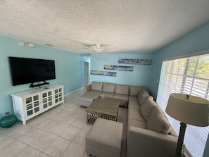 A living room with a flat-screen TV, a sofa, a cabinet, and artwork on the wall.